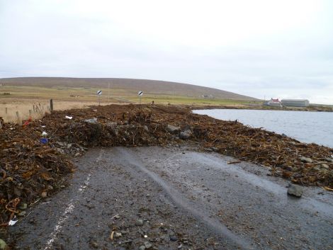 The north road at Haroldswick under three feet of beach debris was still being cleared on Tuesday, three days after the storm. Pic. Jack Barclay
