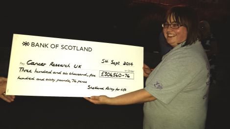 Outgoing Relay for Life committee chairwoman Kerry Eunson with an enormous cheque for 2014's herculean effort.