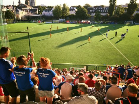 Team Shetland cheering on the footballers, who put up a great fight before losing 3-1 to the Isle of Man. They face Menorca in tomorrow's bronze medal playoff. Photo: BBC Radio Shetland/Jane Moncrieff