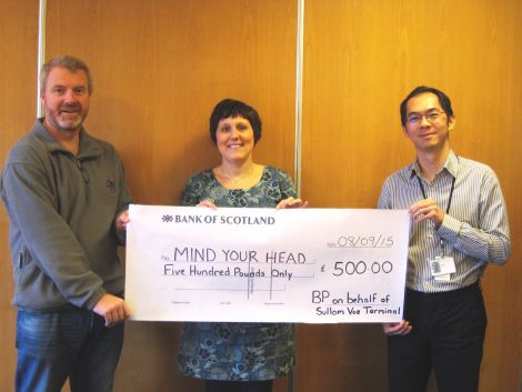 The terminal's charity appeals committee chairman Graham Hughson (left) hands Anouska Civico of Mind Your Head the big cheque, with instrument and control engineer Andrian Harsono.