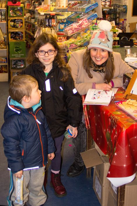 Elsbeth Stewart Clark signs a copy of her book Robin's Red Christmas for three-year-old Filip and Sonia Poniecki, aged eight, in the Aywick Shop at the start of her book signing tour of the isles – Photo: Charlie Inkster
