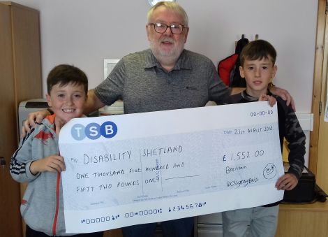 Benji and Dougray Bain presenting a cheque for £1,552 to Disability Shetland vice-chairman George McGhee.