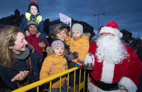 Santa claus with a group of children in front of a fence.