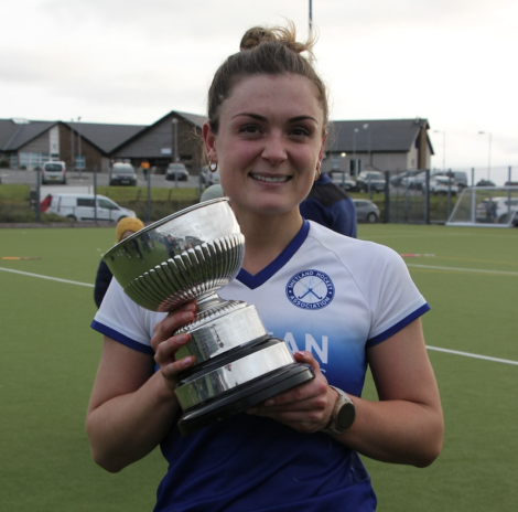 Female athlete holding a trophy on a sports field.