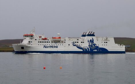 A northlink ferry with a blue and white viking-themed livery sailing on calm waters.