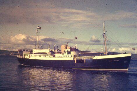 Vintage passenger ship sailing on calm waters with a clear sky in the background.