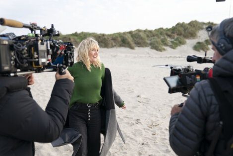 Woman being filmed on a beach for a production.