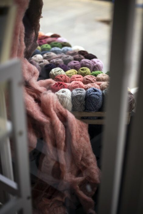 Various colored yarn balls arranged on a shelf, viewed through a blurred foreground.