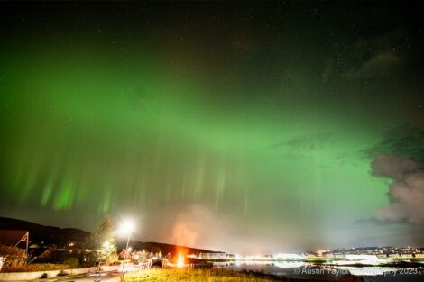 A green aurora bore over a city.