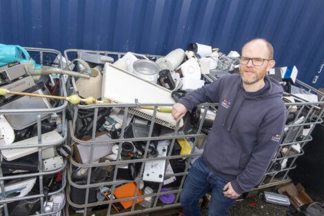 A man standing next to a pile of electronic waste.