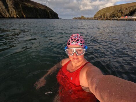 A woman in a red swimsuit taking a selfie in the water.