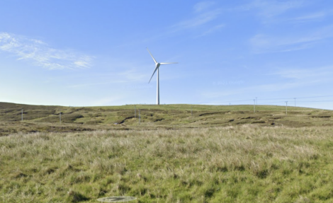 A windmill on a grassy hill.