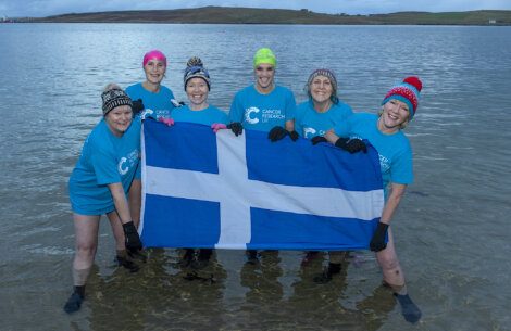 A group of people holding a scottish flag in the water.
