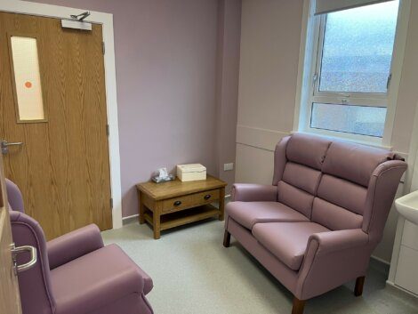A room with two purple chairs and a window.