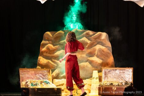 A woman standing on a stage with smoke coming out of it.