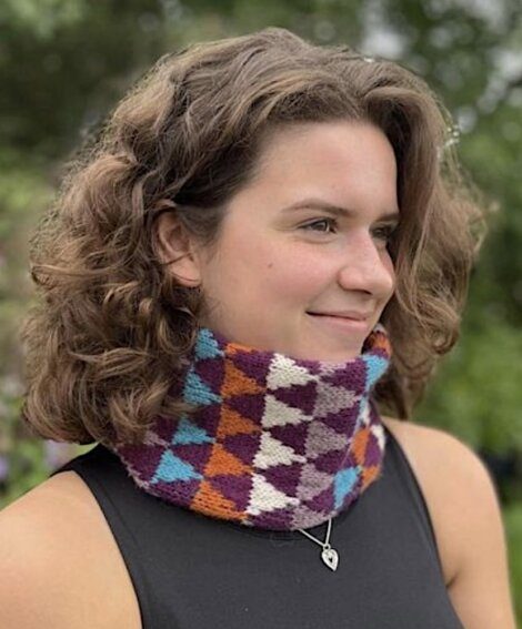 A young woman wearing a colorful knitted neck warmer.