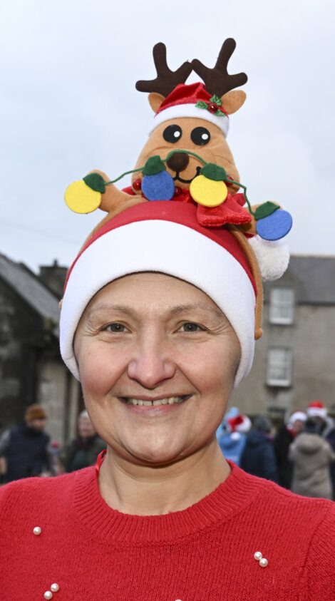 A woman wearing a santa hat with a stuffed animal on her head.
