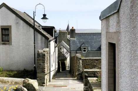 A narrow street lined with stone buildings and a lamp post.