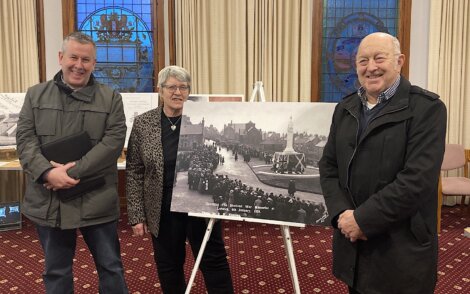 Three people standing in front of a picture of a church.
