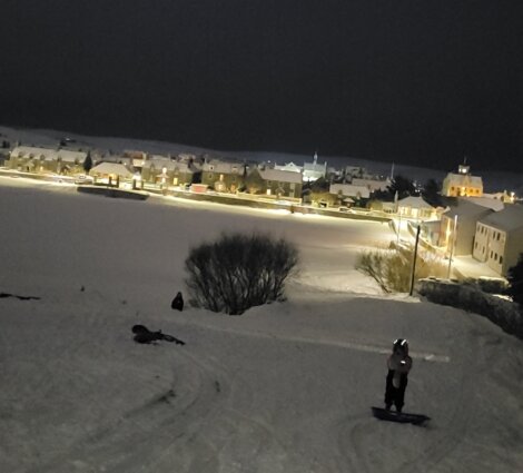 A person is snowboarding down a hill at night.