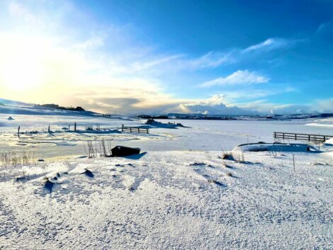 The sun is shining on a snow covered field.