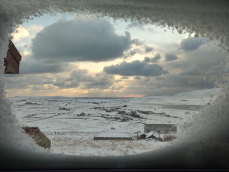 A view of a snowy landscape through a window.