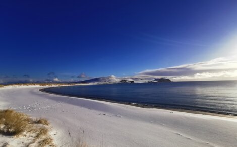 A beach covered in snow on a sunny day.