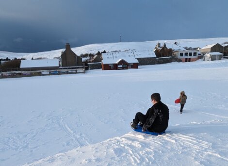 Two people sledding down a snowy hill.