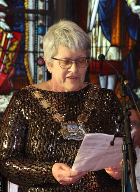 A woman is holding a piece of paper in front of a stained glass window.