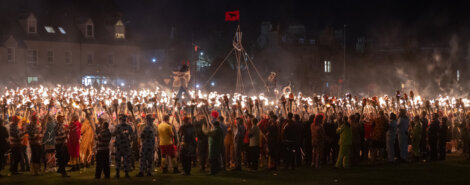 A large group of people holding torches at night.