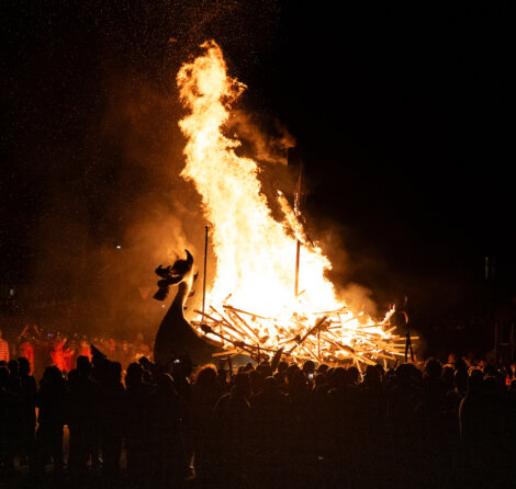 A large group of people watching a bonfire.