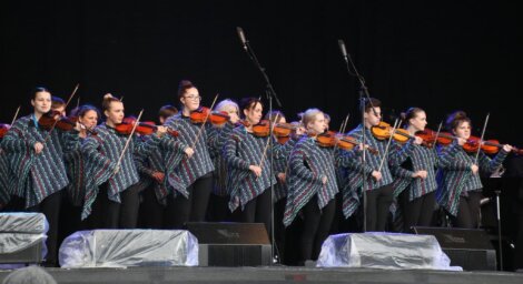 A group of women playing violins on stage.