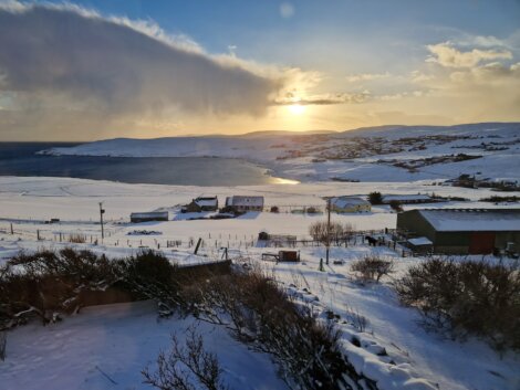 The sun is setting over a snow covered landscape.