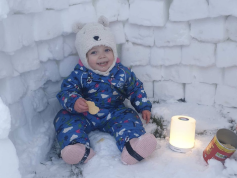 A baby sitting in the snow with a candle.
