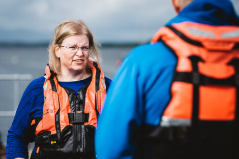 A woman in a life jacket talking to another person.