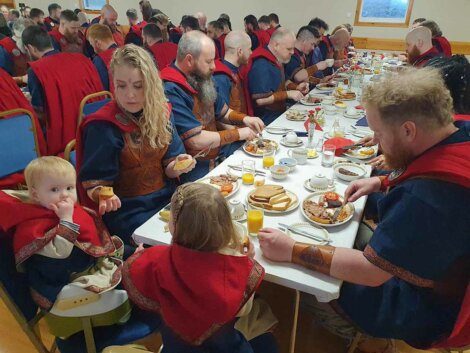People dressed in medieval-style clothing dining at a long table.