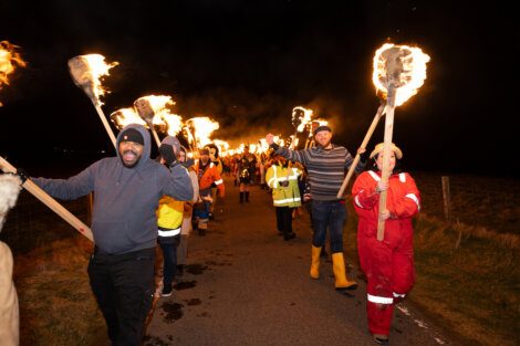 People participating in a torchlight procession at night.