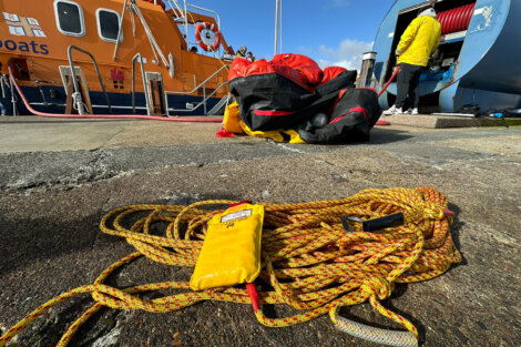 Rescue gear laid out on the dock with a lifeboat in the background.