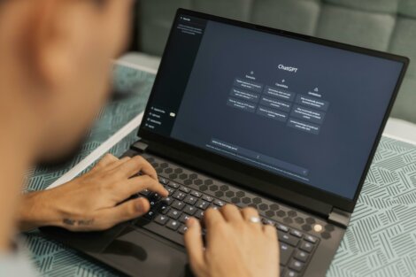 Person typing on a laptop with a website interface displayed on the screen.
