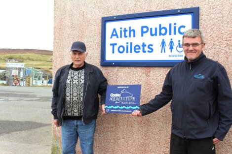 Two men standing beside a sign that reads 